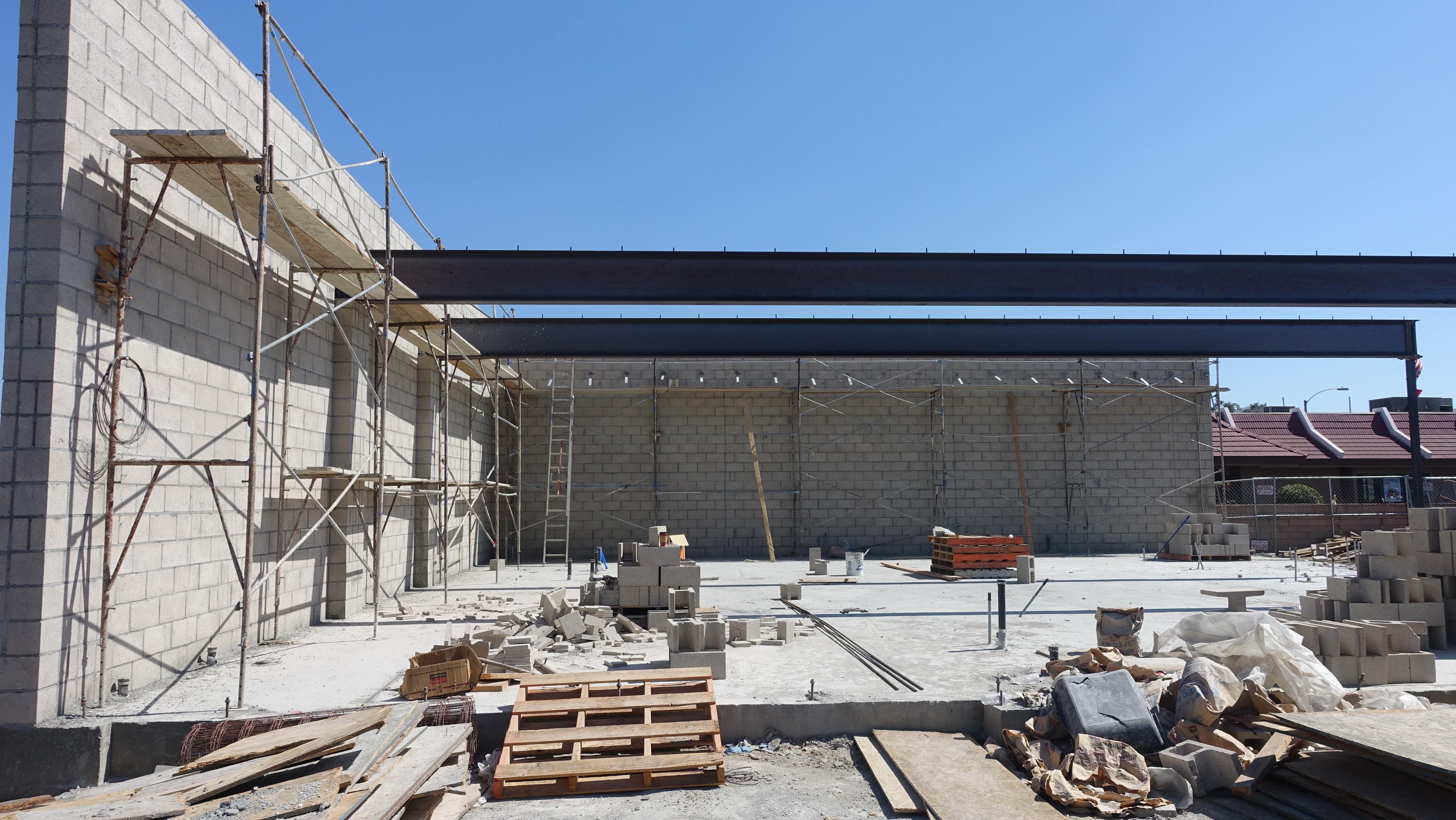 Active commercial construction site with steel beam framing and concrete block walls - Dashing Properties Inc.
